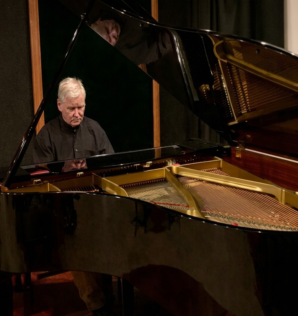 Ronald Tomarelli in concert, seated at a grand piano