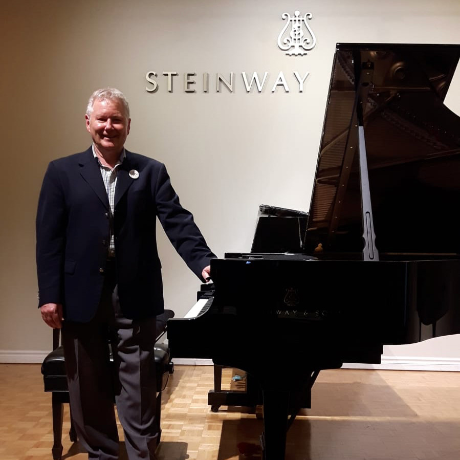 Ronald Tomarelli, Steinway Artist, standing beside a Steinway grand piano