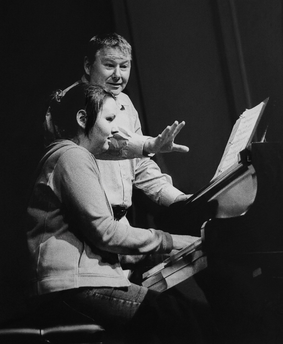 Ronald Tomarelli teaching a piano lesson, guiding a student's hands on the keyboard